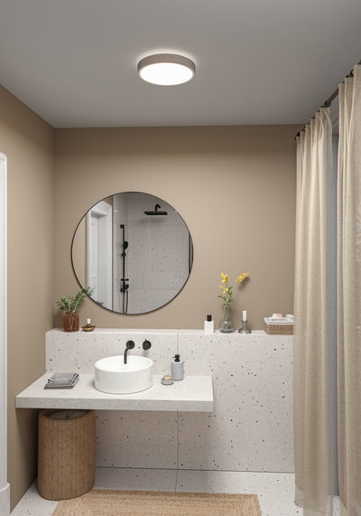 Rundes Deckenlicht mit Stoffrand in Beige beleuchtet modernes Badezimmer mit Terrazzo-Waschtisch.