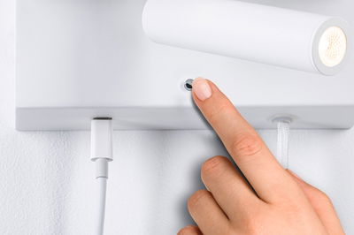 White LED wall light with round switch and textile cable, hand operated, modern indoor lighting