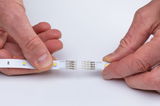 Hands connecting two white LED strips with 12V DC connectors for flexible lighting setups.