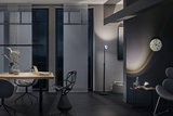 Moderne stue med sort gulvlampe, grå stole og træbord i mørkt stilfuldt interiør.