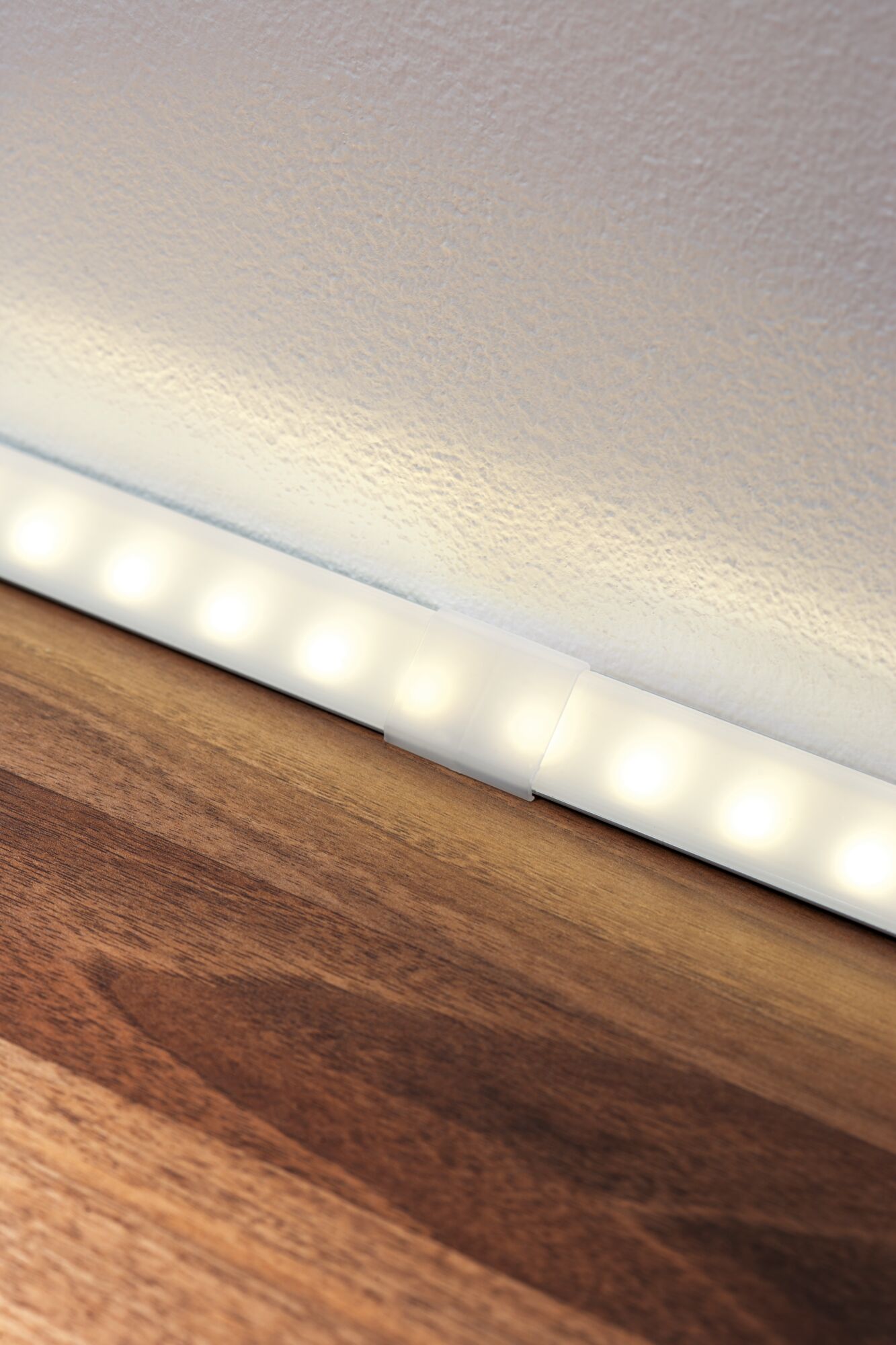 Weiße LED-Lichtleiste mit warmweißem Licht auf Holzoberfläche für moderne Raumbeleuchtung