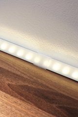 White LED light strip with warm white light on wooden surface for modern room lighting