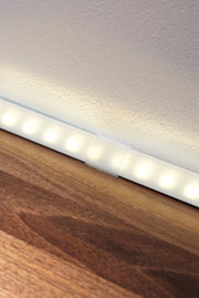 White LED light strip with warm white light on wooden surface for modern room lighting