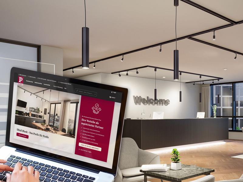 Modernes Büro mit schwarzem ProRail 3 Schienensystem und Laptop mit Paulmann Webseite.