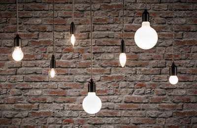 Verschiedene Filament-Glühbirnen mit schwarzer Fassung vor roter Backsteinwand, Beleuchtung und Lampen.