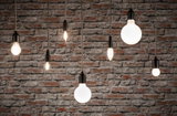 Verschiedene Filament-Glühbirnen mit schwarzer Fassung vor roter Backsteinwand, Beleuchtung und Lampen.
