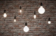 Verschiedene Filament-Glühbirnen mit schwarzer Fassung vor roter Backsteinwand, Beleuchtung und Lampen.