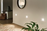 Three white LED wall lights on beige wall in modern hallway with mirror and plant
