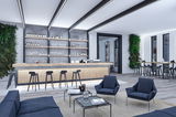 Intérieur lounge moderne avec bar en bois, tabourets noirs, fauteuils bleus et éclairage LED élégant.