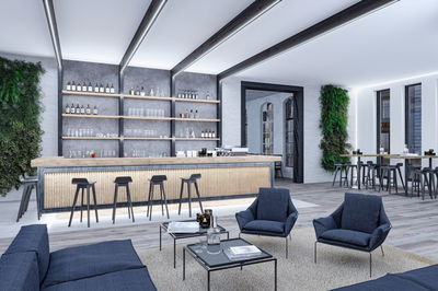 Intérieur lounge moderne avec bar en bois, tabourets noirs, fauteuils bleus et éclairage LED élégant.