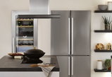 Moderne Küche mit Edelstahl-Kühlschrank, Weinkühler und Kochinsel mit schwarzem Kochfeld und Dunstabzug.