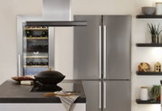 Moderne Küche mit Edelstahl-Kühlschrank, Weinkühler und Kochinsel mit schwarzem Kochfeld und Dunstabzug.