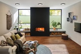 Modern living room with black fireplace, wooden floor, white walls, and round ceiling lights.