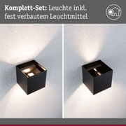 Schwarze Außenwandleuchte mit integriertem Leuchtmittel, Lichtstrahl nach oben und unten an weißer Wand