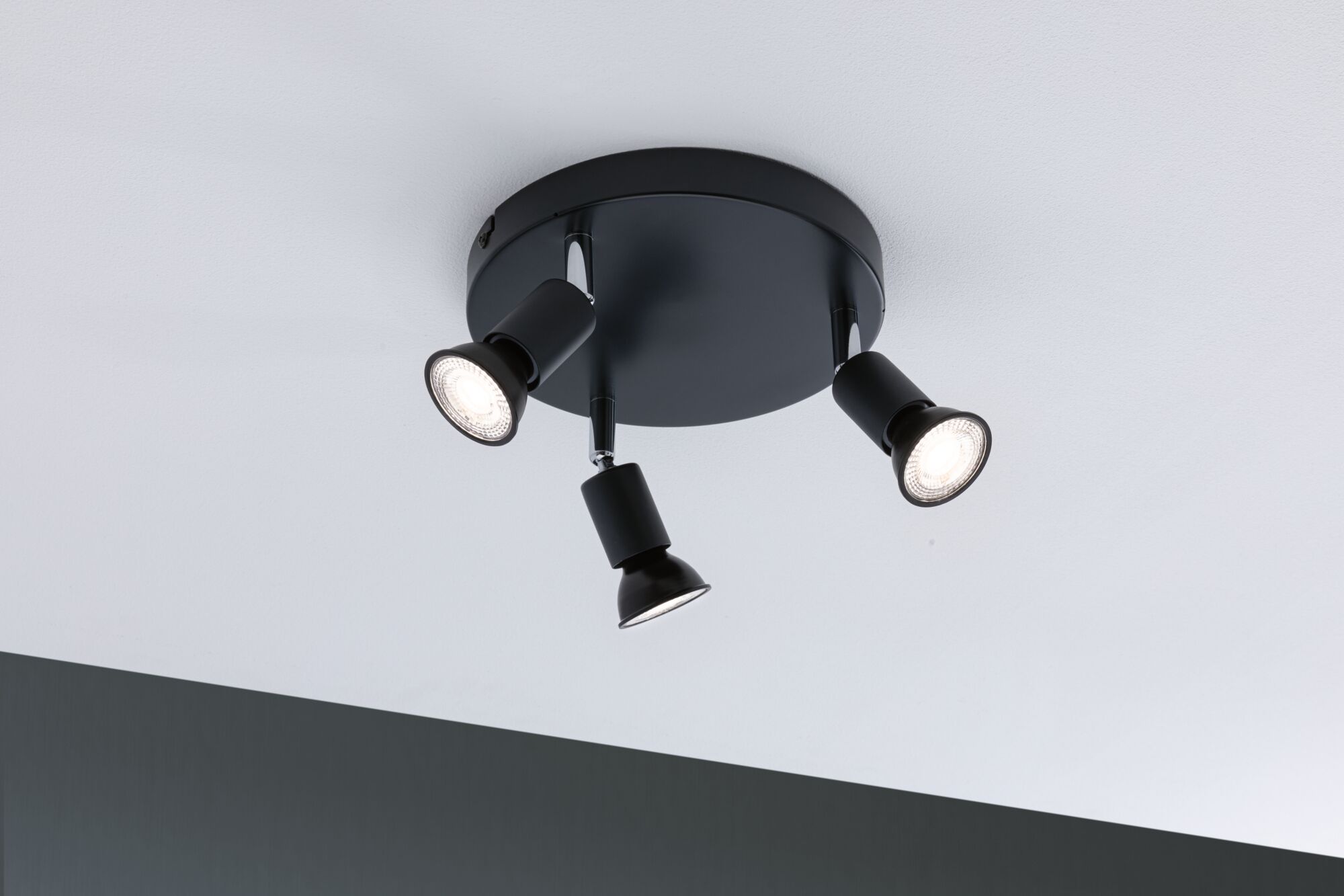 Sort loftlampe med tre justerbare metalspots til målrettet belysning.