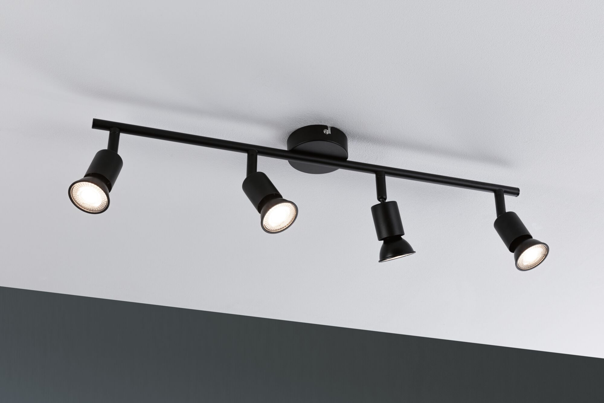 Plafonnier noir avec quatre spots métalliques réglables pour un éclairage moderne.