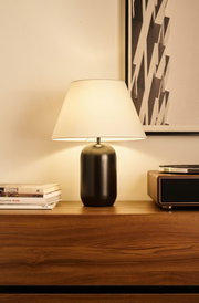 Moderne Tischlampe mit schwarzem Metallfuß und weißem Stoffschirm auf Holzkommode im Wohnzimmer