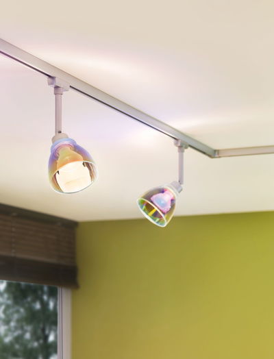 Zwei schwenkbare Deckenstrahler mit transparenten, irisierenden Glaslampenschirmen in modernem Wohnraum.