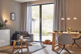 Modernes Wohnzimmer mit grauem Sessel, Holztisch, Glas-Couchtisch und stilvollen Pendelleuchten.