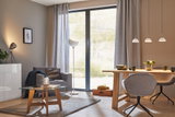 Moderne stue med grå lænestol, træbord, glas sofabord og stilfulde pendellamper.