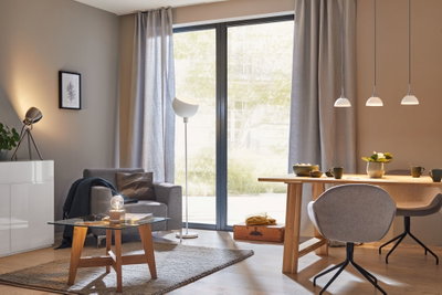 Moderne stue med grå lænestol, træbord, glas sofabord og stilfulde pendellamper.