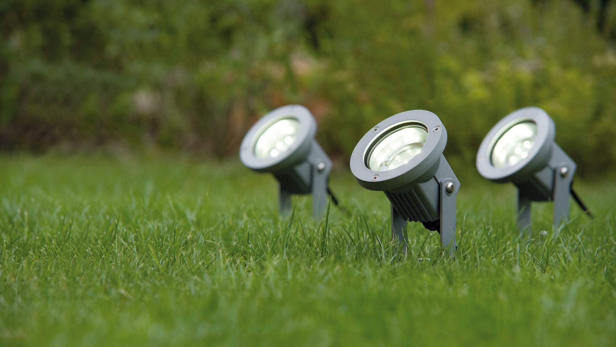 Drei graue LED-Erdspieße aus Metall im grünen Gras für Gartenbeleuchtung und Außenlicht.