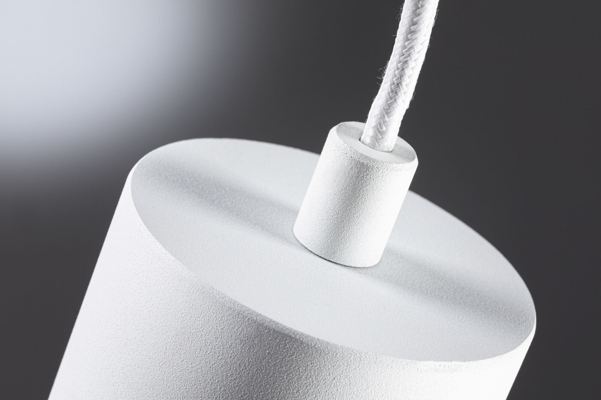 Nærbillede af hvid tekstureret lampesokkel med stofkabel til moderne LED-belysning