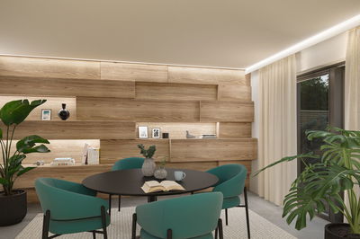 Modernes Esszimmer mit schwarzem Tisch, türkisfarbenen Stühlen und Holzpaneelwand mit LED-Beleuchtung