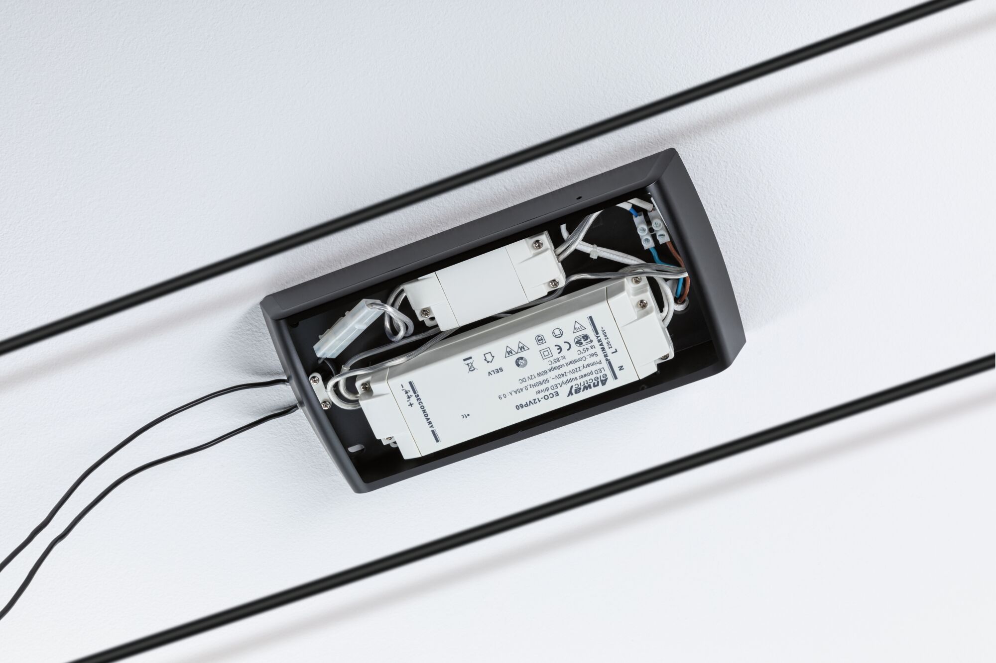 Åbent sort kabinet med hvid LED-driver og kabler monteret på hvidt loft