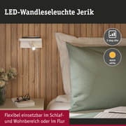 Weiße LED-Wandleseleuchte Jerik mit warmweißem Licht an Holzwand neben Bett und Nachttisch