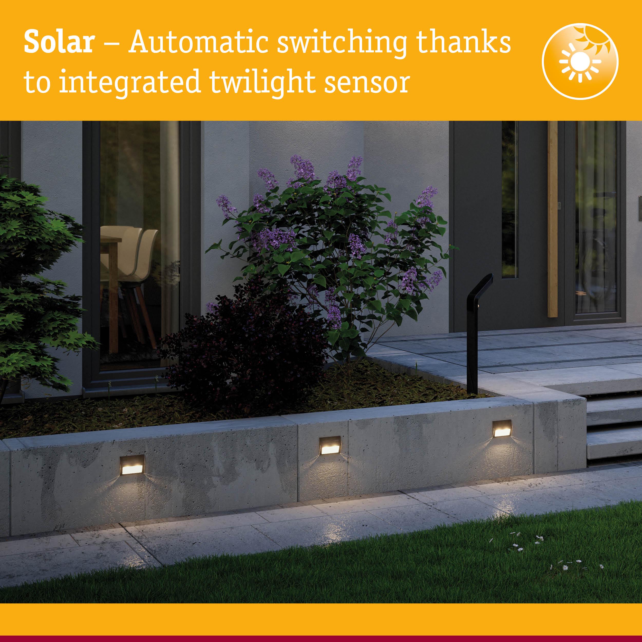 Solar outdoor wall lights with integrated twilight sensor mounted on grey concrete wall in garden