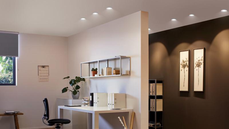 Modern office with white walls, black chair, and multiple ceiling downlights providing bright work lighting.
