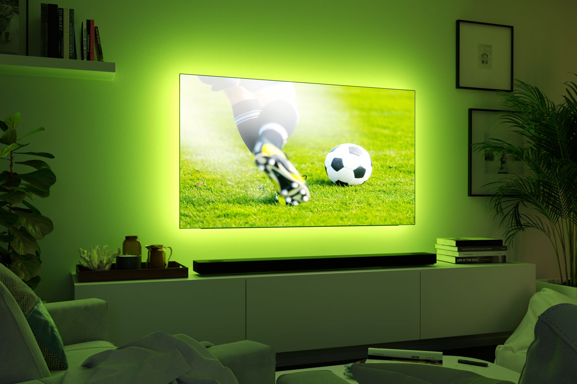 Flacher Fernseher mit grünem LED-Hintergrundlicht in modernem Wohnzimmer mit Pflanzen und Büchern
