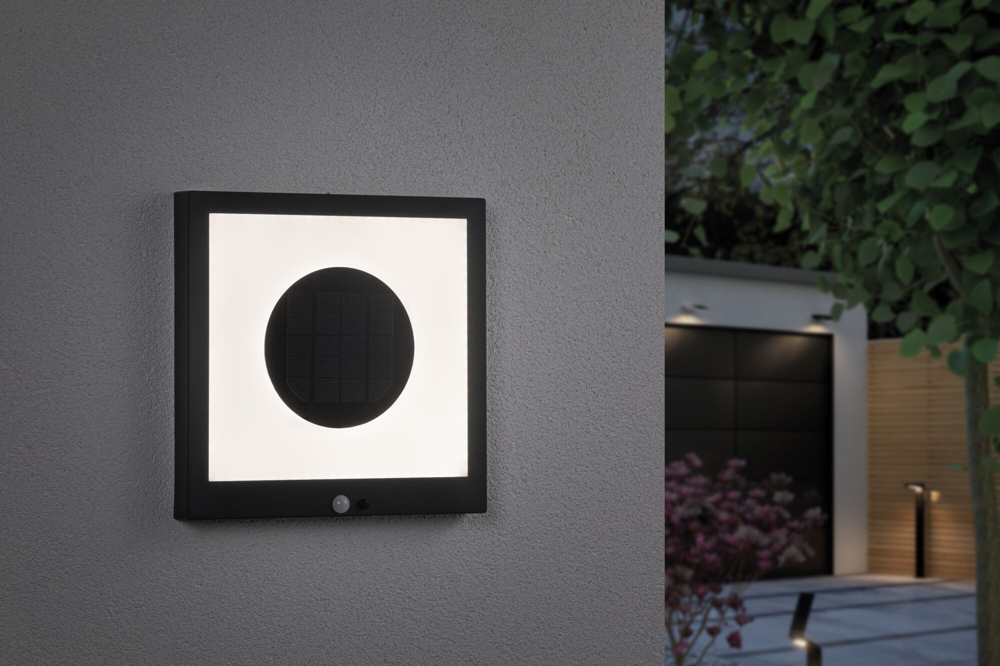 Schwarze quadratische Solar-Wandleuchte mit Bewegungsmelder an grauer Hauswand für Außenbeleuchtung