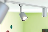 Projecteur LED gris en métal sur rail avec fond vert pour éclairage intérieur moderne