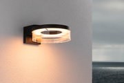 Modern black LED wall light with round acrylic glass and warm white light for outdoor use.