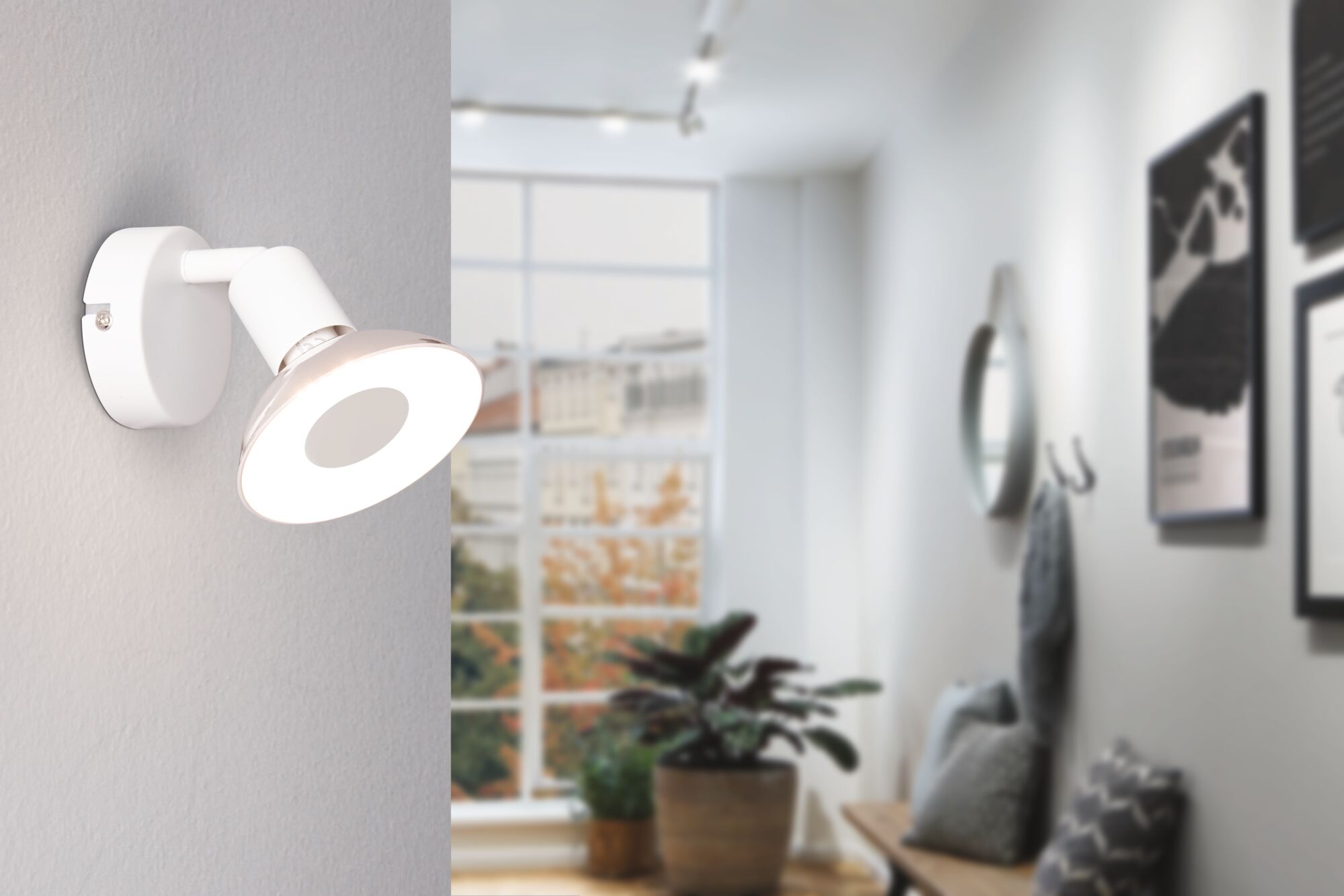 Modern white metal LED wall spotlight in living room with window and plants.