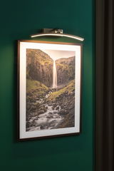 LED-licht in geborsteld metaal boven watervallandschapsfoto aan groene muur