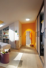Moderne slaapkamer met lichte houten vloer, wit meubilair en plafondlamp voor warme verlichting.