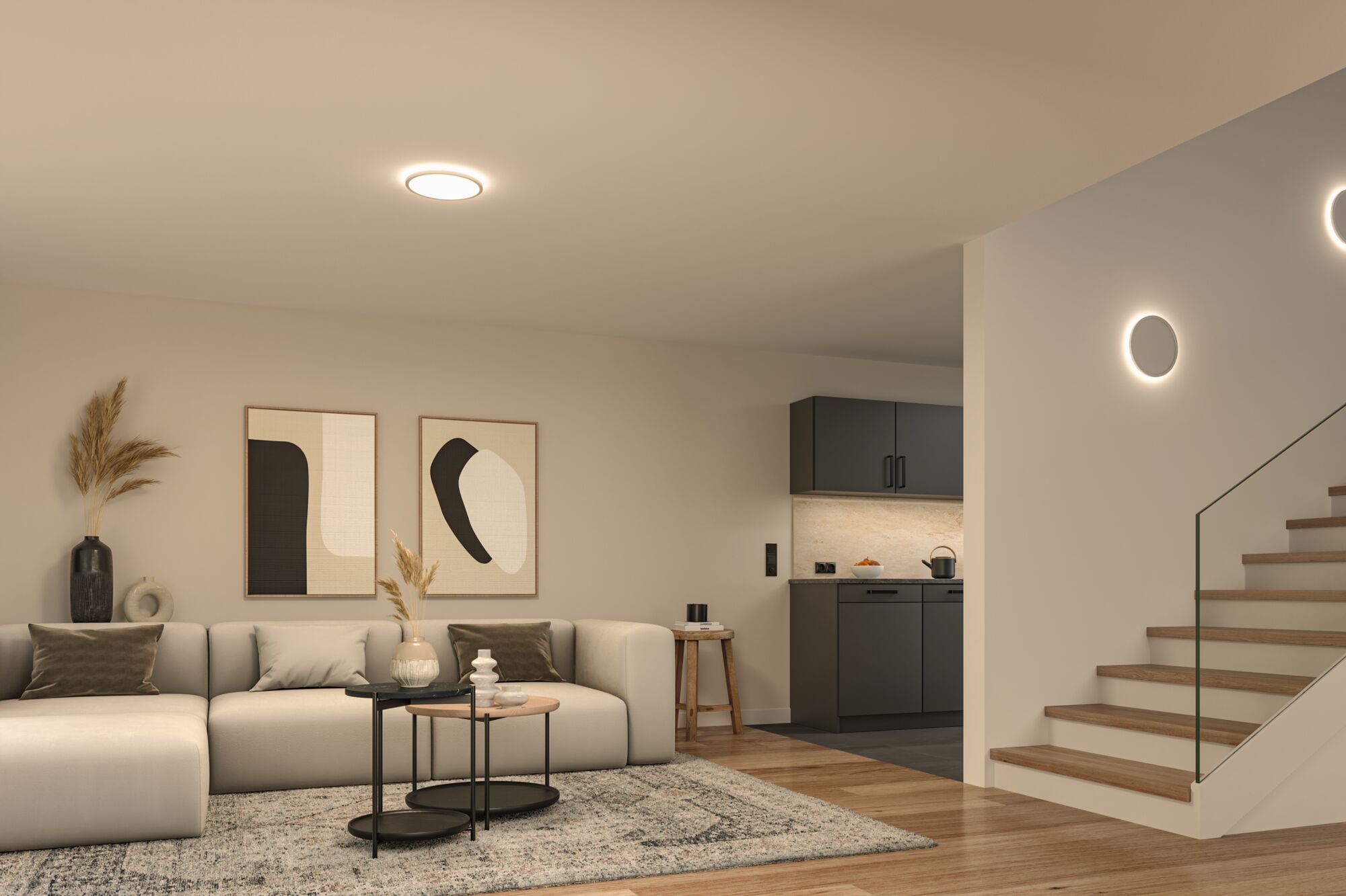 Moderne stue med rund loftslampe og væglamper i varmt hvidt lys, trætrappe og grå sofa.