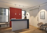 Espace d'accueil moderne avec comptoir noir et blanc, accents muraux rouges et éclairage de plafond réglable.