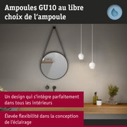 Salle de bain moderne avec miroir rond, suspensions blanches, étagère en bois avec plantes et produits de soin