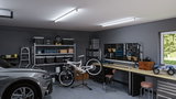 Moderne garage met grijze auto, fietsreparatiestandaard en LED-plafondlampen voor helder werklicht