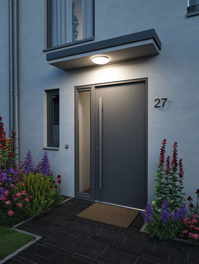 Modern anthracite front door with large handle and LED ceiling light illuminating the entrance area.