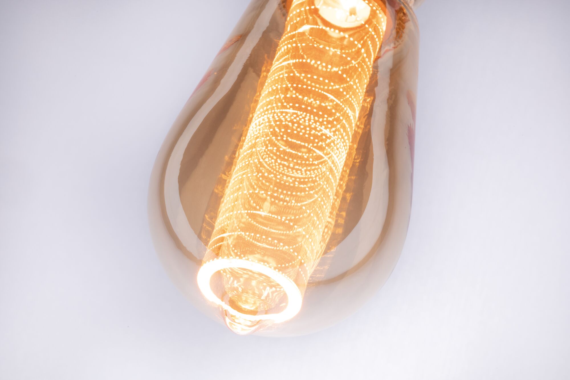 Nahaufnahme einer warmweißen LED-Glühbirne mit dekorativem Lichtmuster und bernsteinfarbenem Glas
