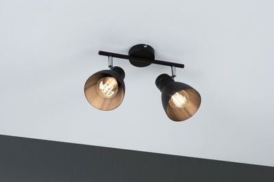 Schwarze Deckenleuchte mit zwei verstellbaren Metallstrahlern und warmweißem Licht für Wohnräume.