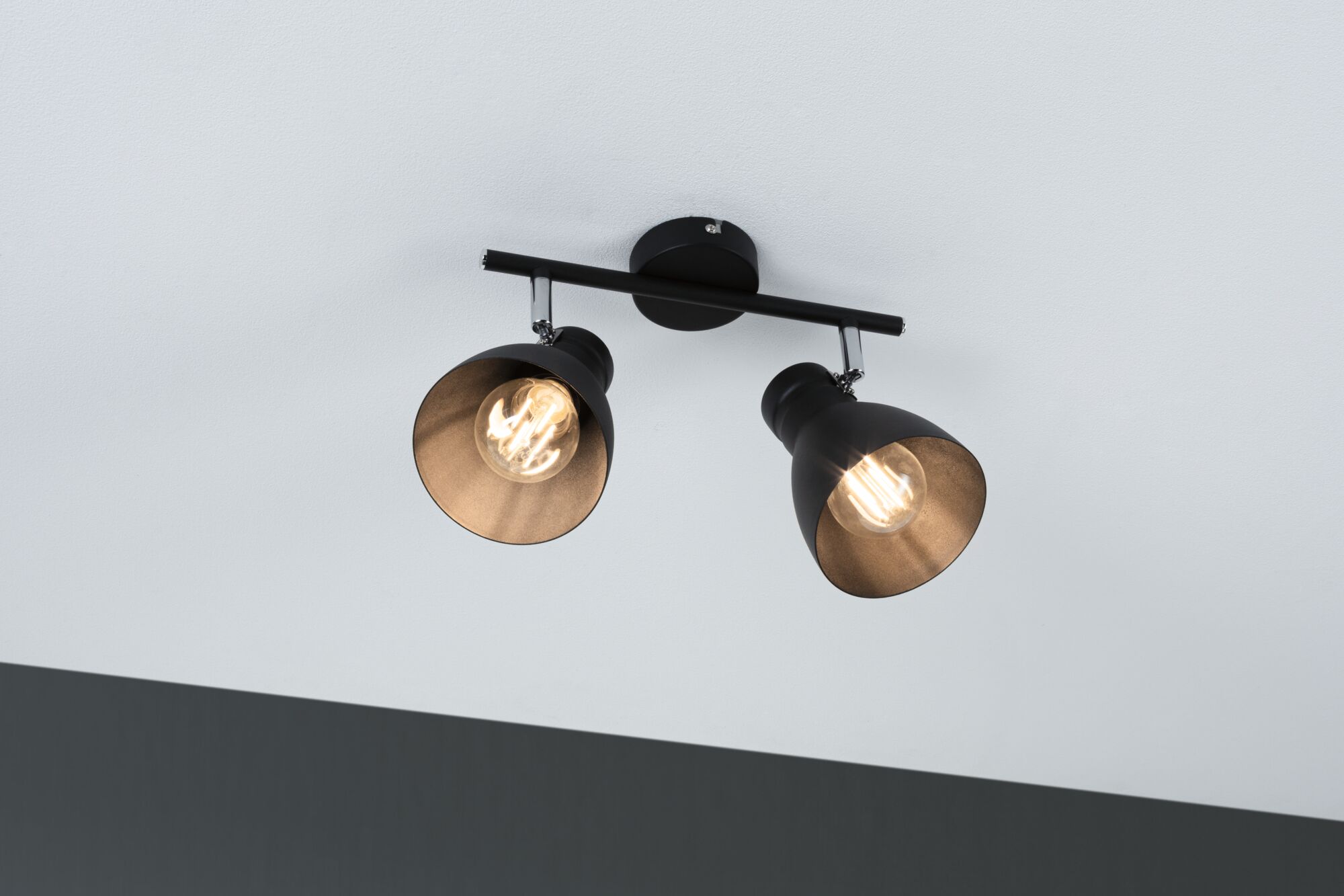 Black ceiling light with two adjustable metal spotlights and warm white light for living spaces.