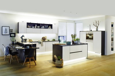 Cuisine moderne avec façades blanc-noir et éclairage LED blanc chaud sous les meubles pour ambiance chaleureuse