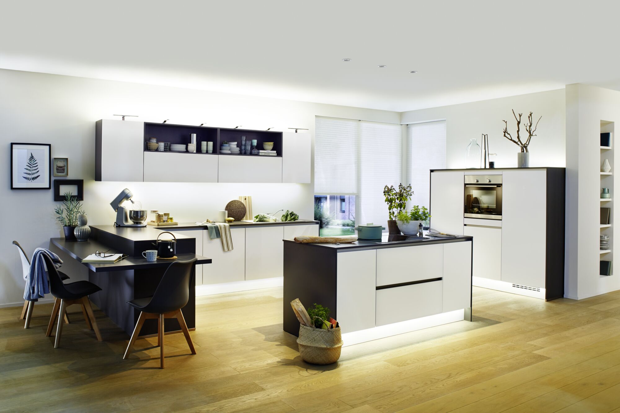 Cuisine moderne avec façades blanc-noir et éclairage LED blanc chaud sous les meubles pour ambiance chaleureuse