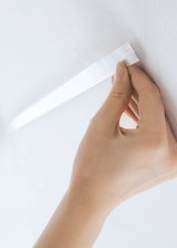 Hand befestigt weiße selbstklebende LED-Lichtleiste an weißer Wand für flexible Beleuchtung